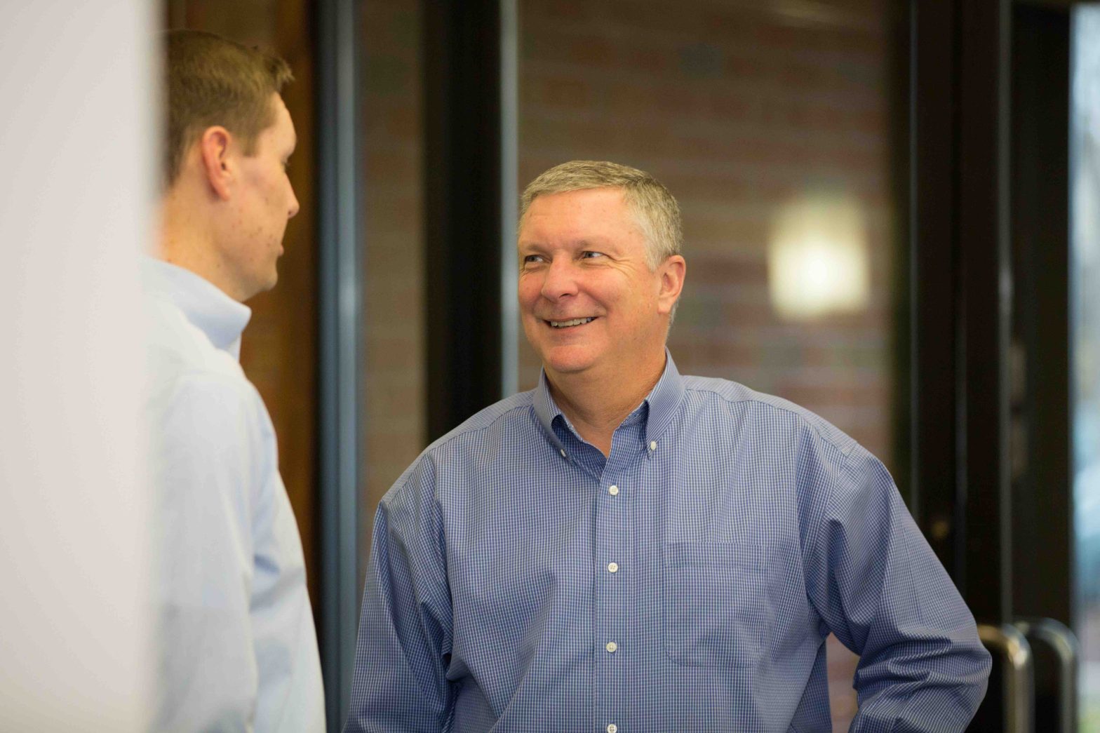 Two men smiles while talking to each other