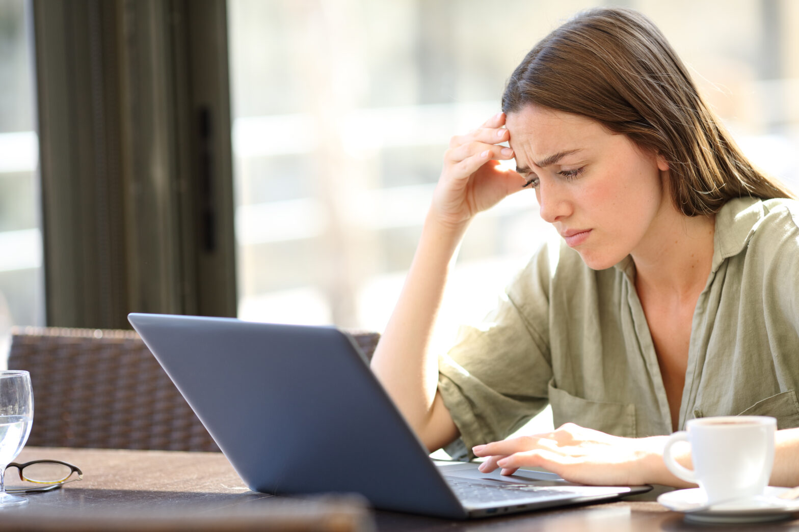 woman staring at laptop with hand on head, frustrated by job search. She should call The Lee Group.